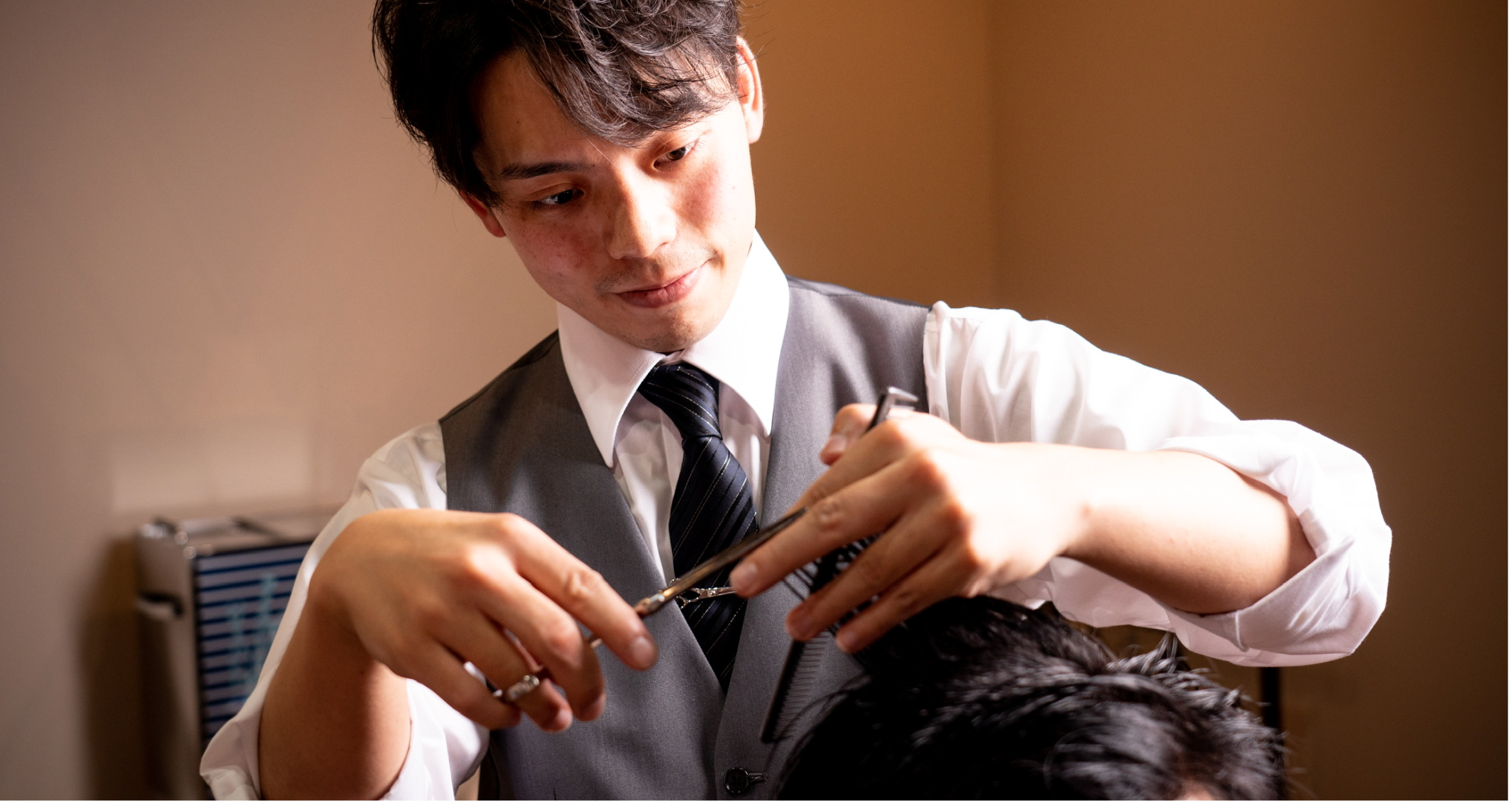 札幌の高級理容室で、丁寧にカットを行う理容師の男性
