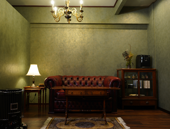 札幌の高級理容室の待合スペースにある、クラシックなソファとアンティーク家具が並ぶ落ち着いた空間